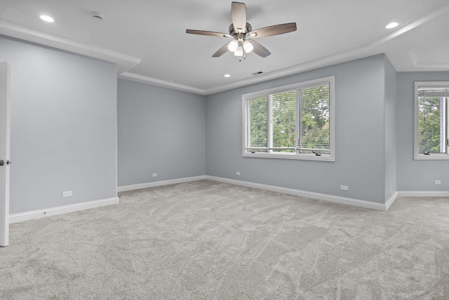 empty room featuring ceiling fan, light colored carpet, and a wealth of natural light