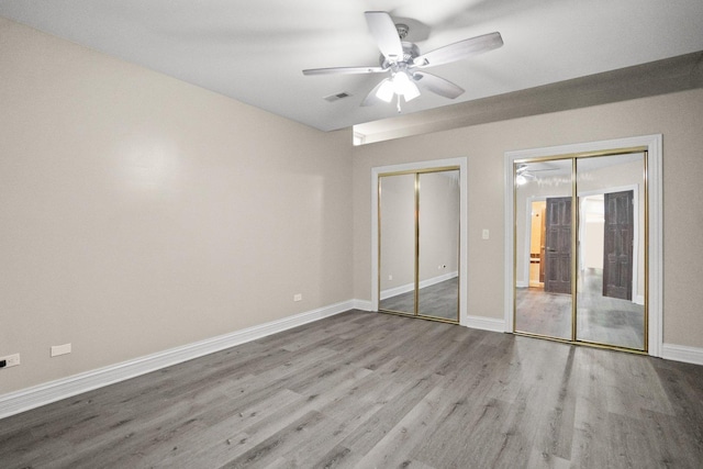 unfurnished bedroom with two closets, ceiling fan, and light hardwood / wood-style flooring