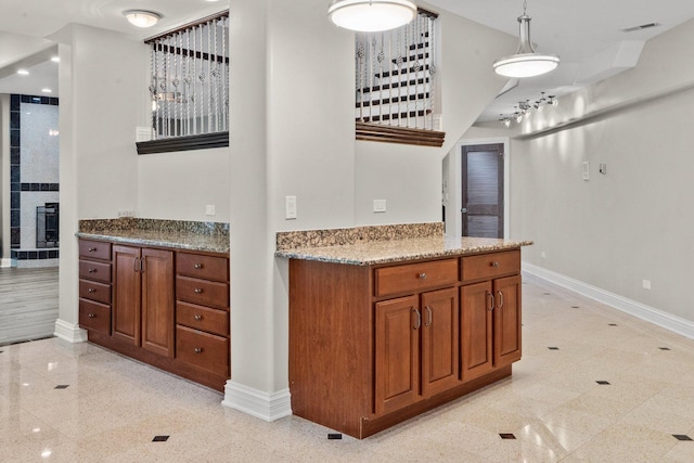 kitchen with a tile fireplace, pendant lighting, and light stone counters