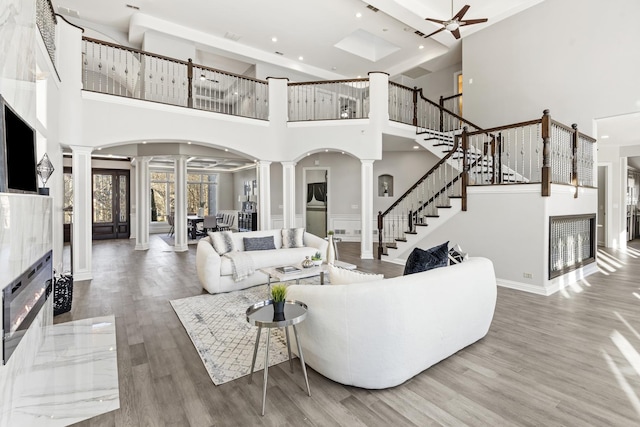 living room featuring ceiling fan, a fireplace, hardwood / wood-style floors, and ornate columns