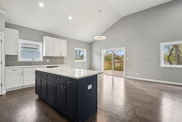 kitchen with decorative backsplash, dark hardwood / wood-style flooring, decorative light fixtures, a center island, and white cabinetry