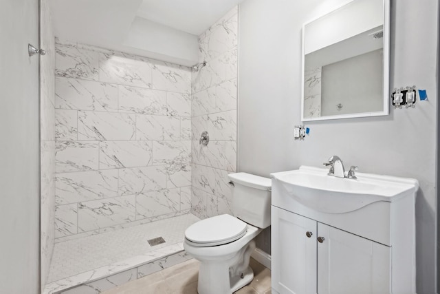 bathroom with tiled shower, vanity, and toilet