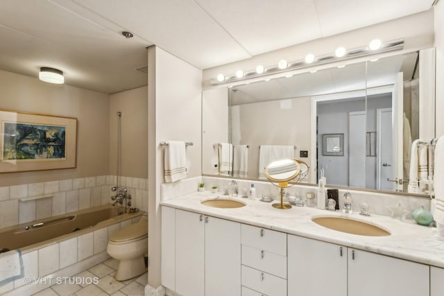 bathroom featuring tile patterned flooring, vanity, tiled bath, and toilet