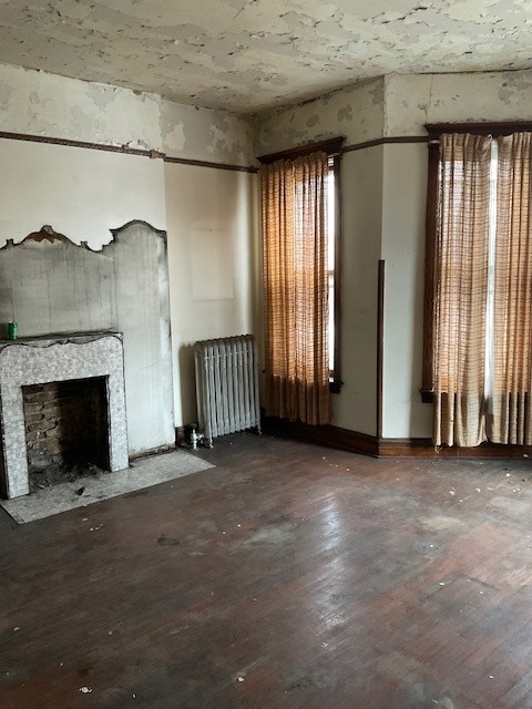 unfurnished living room with dark hardwood / wood-style flooring and radiator