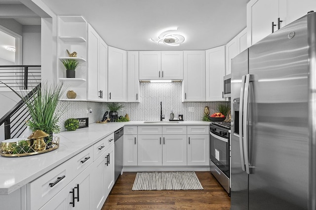 kitchen featuring backsplash, stainless steel appliances, dark wood-type flooring, sink, and white cabinets