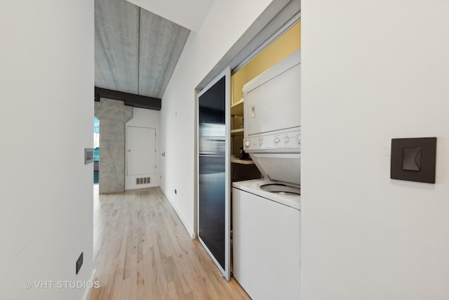 clothes washing area featuring light hardwood / wood-style floors and stacked washer / dryer