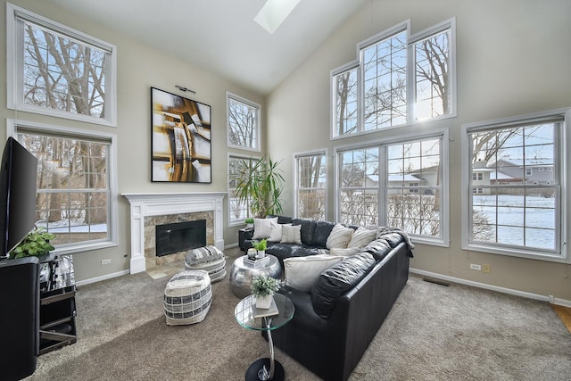 carpeted living room with a fireplace, a healthy amount of sunlight, high vaulted ceiling, and a skylight