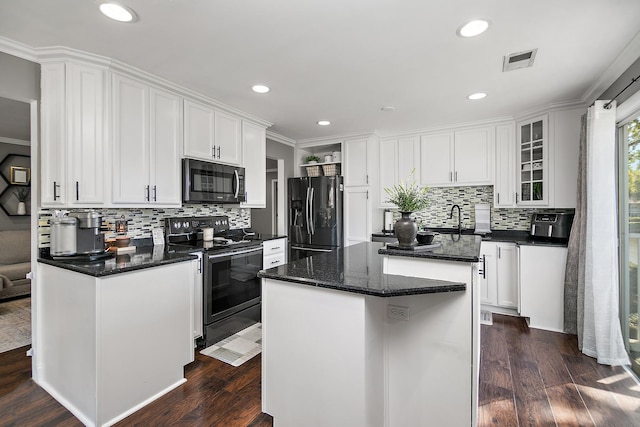 kitchen with stainless steel range with electric cooktop, white cabinets, black fridge, ornamental molding, and a kitchen island