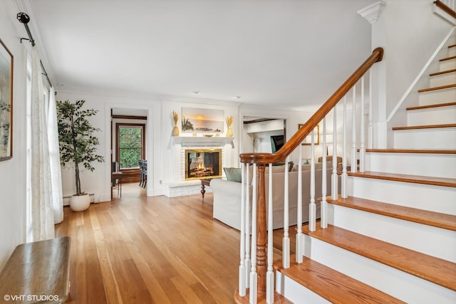 stairway featuring hardwood / wood-style flooring, baseboard heating, and crown molding