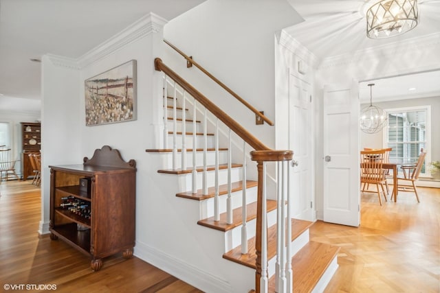 stairway with crown molding and a notable chandelier