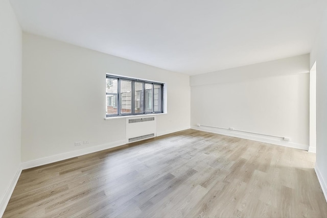 spare room with light wood-type flooring and radiator