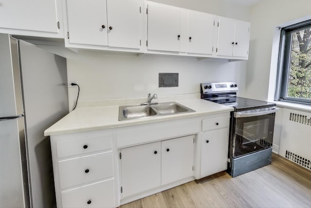 kitchen featuring white cabinets, sink, light hardwood / wood-style floors, radiator heating unit, and stainless steel appliances