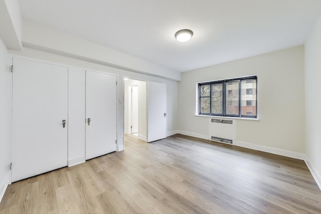 unfurnished bedroom with light hardwood / wood-style flooring and radiator