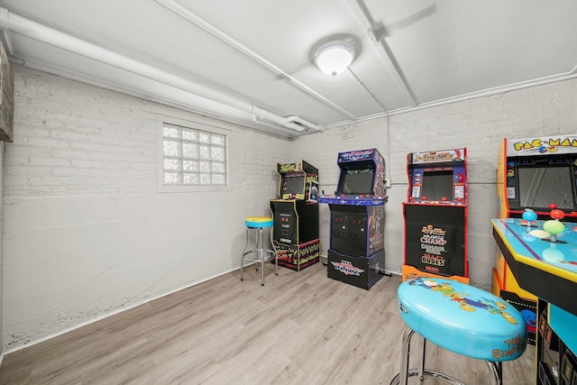 recreation room with hardwood / wood-style flooring and brick wall