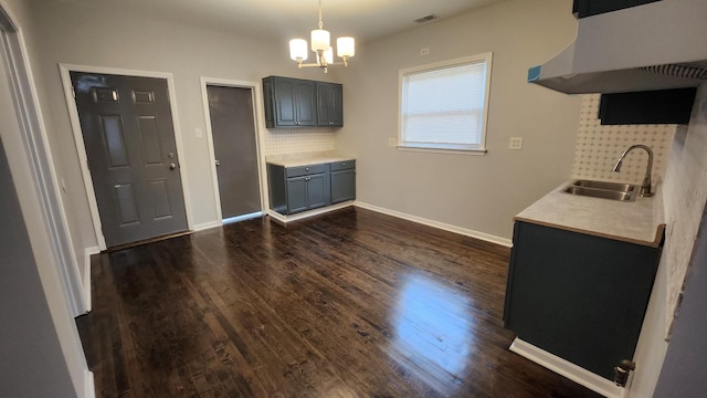 unfurnished dining area featuring sink, dark wood-type flooring, and an inviting chandelier