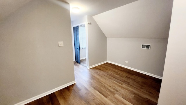 additional living space with hardwood / wood-style floors and vaulted ceiling