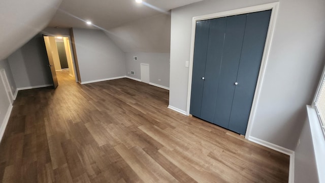 additional living space with hardwood / wood-style floors and lofted ceiling