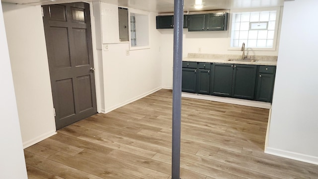 basement featuring electric panel, sink, and light hardwood / wood-style floors