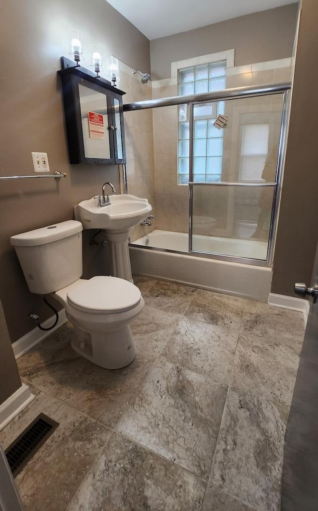 bathroom with toilet and combined bath / shower with glass door