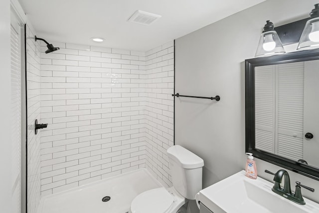 bathroom with a tile shower, vanity, and toilet