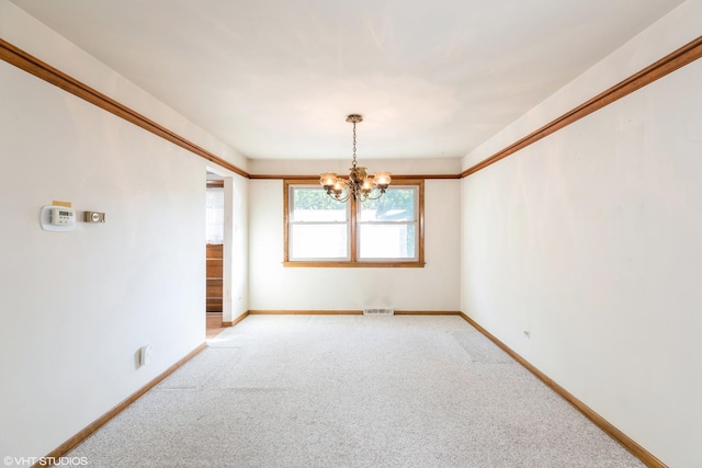 carpeted spare room with a chandelier