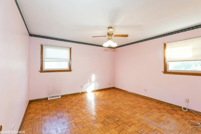 empty room with light parquet flooring, plenty of natural light, and ceiling fan