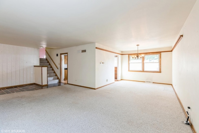 carpeted spare room with an inviting chandelier