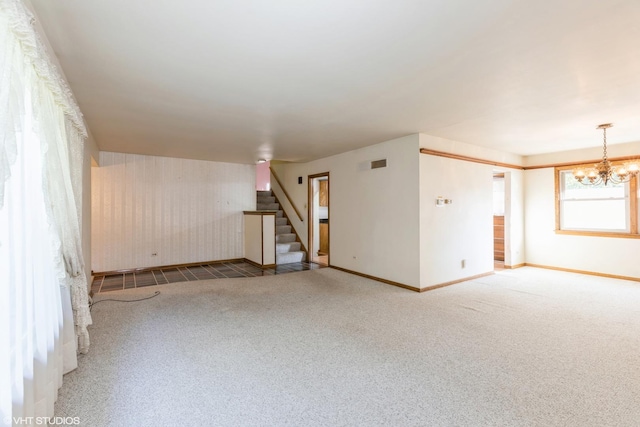 spare room featuring carpet floors and a notable chandelier