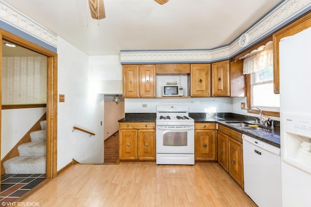 kitchen featuring light hardwood / wood-style floors, white appliances, sink, and dark stone counters