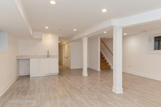 basement with light hardwood / wood-style floors and sink