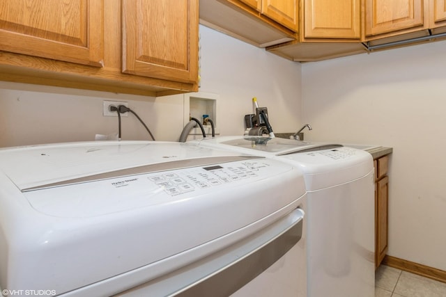 laundry area featuring washer and clothes dryer, light tile patterned flooring, and cabinets