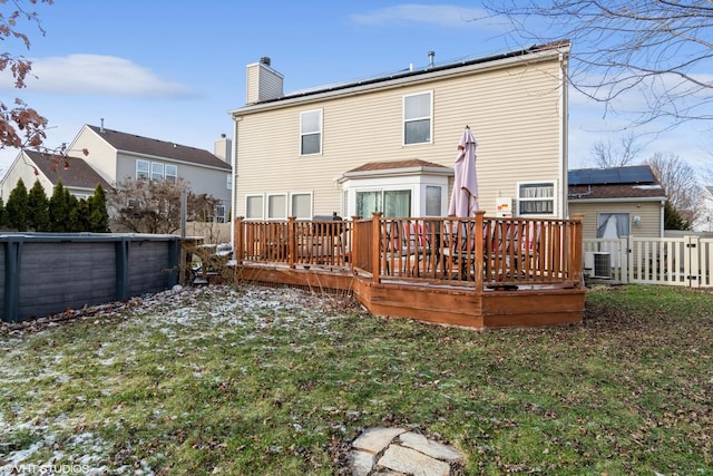 back of house with a lawn, solar panels, and a wooden deck