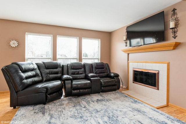 home theater room featuring plenty of natural light, wood-type flooring, and a tiled fireplace