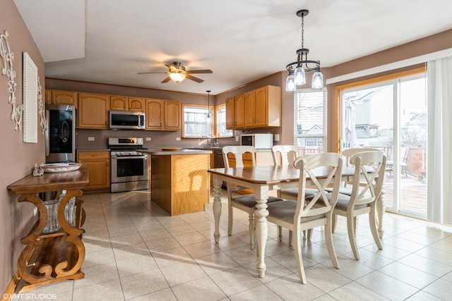 kitchen featuring light tile patterned flooring, hanging light fixtures, ceiling fan, appliances with stainless steel finishes, and a kitchen island