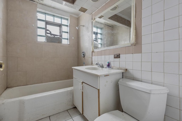 full bathroom featuring tile patterned floors, toilet, vanity, tile walls, and tiled shower / bath