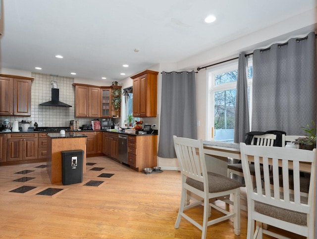 kitchen with a center island, wall chimney exhaust hood, tasteful backsplash, stainless steel dishwasher, and light wood-type flooring