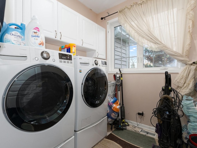 clothes washing area featuring cabinets and separate washer and dryer