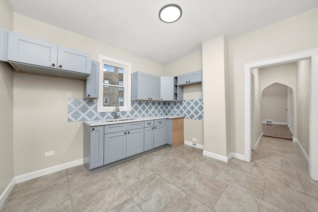 kitchen with tasteful backsplash, gray cabinetry, and sink