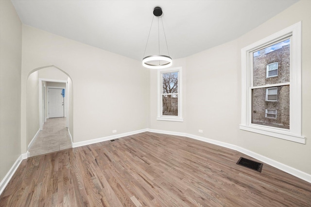 empty room with light hardwood / wood-style flooring and a wealth of natural light