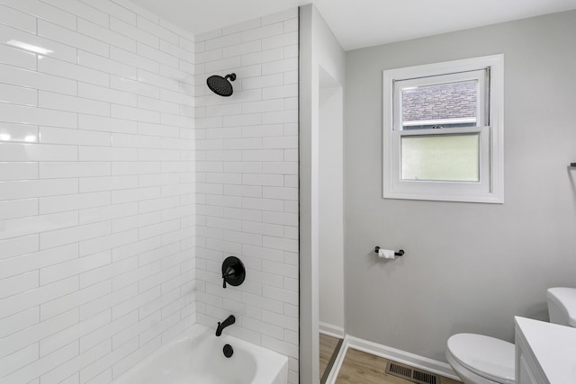 full bathroom featuring vanity, wood-type flooring, tiled shower / bath combo, and toilet