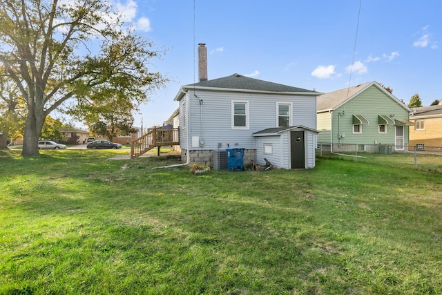 back of house with a lawn, central air condition unit, a storage shed, and a deck