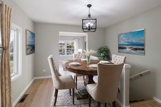 dining space featuring a notable chandelier and light wood-type flooring