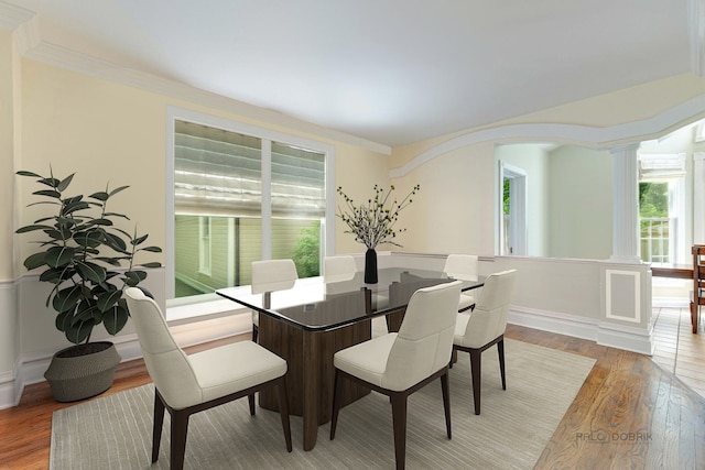 dining area featuring crown molding, wood-type flooring, and decorative columns