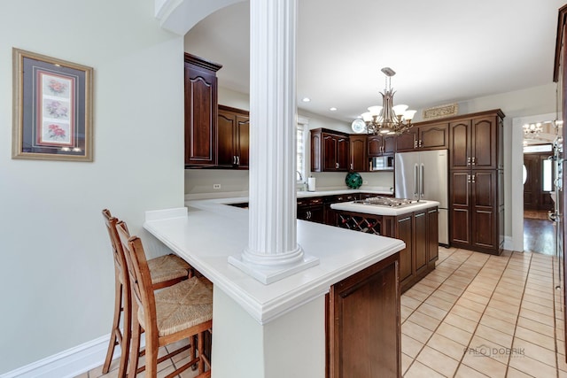 kitchen featuring a peninsula, an inviting chandelier, stainless steel appliances, light countertops, and light tile patterned flooring