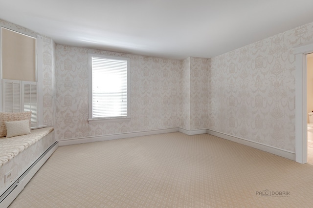 carpeted spare room featuring a baseboard heating unit, baseboards, and wallpapered walls