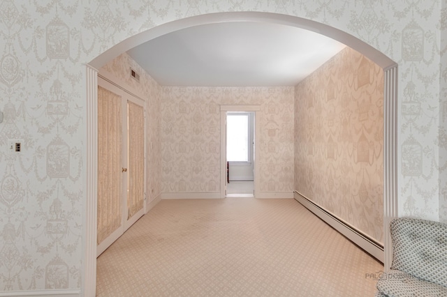 spare room featuring arched walkways, baseboard heating, visible vents, and wallpapered walls