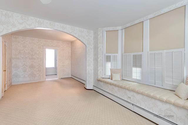 spare room with arched walkways, baseboard heating, and wallpapered walls