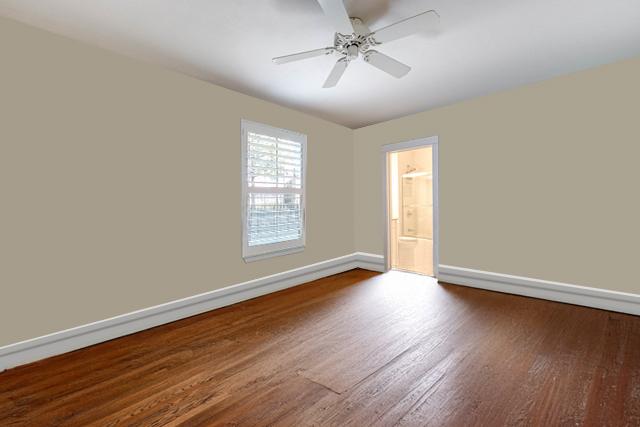 empty room with dark wood finished floors, a ceiling fan, and baseboards