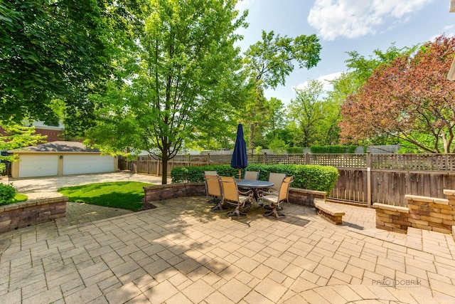 view of patio featuring outdoor dining space, a fenced backyard, and an outdoor structure