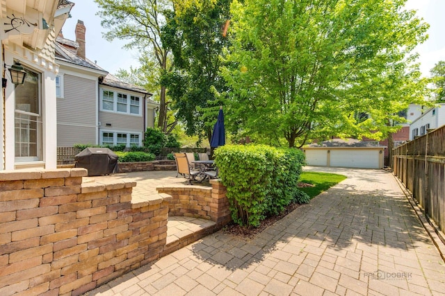 view of patio / terrace featuring fence, a detached garage, and area for grilling